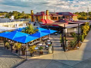 Aerial view of the Esk Grand Hotel including the blue umbrellas over the back outdoor dining area and building.