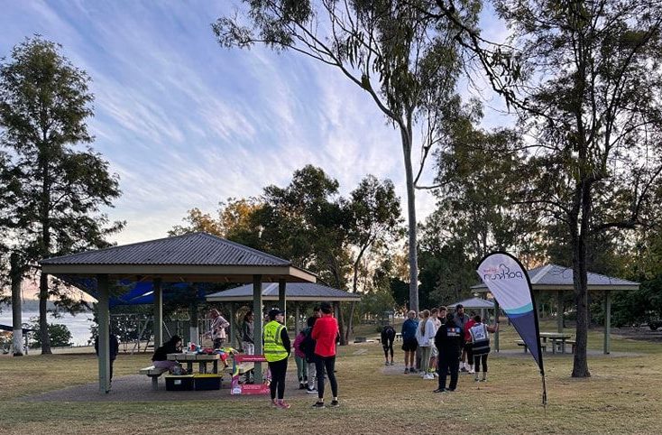 Photo of Cormorant Bay Parkrun attendees standing in the parkland waiting for runners to finish