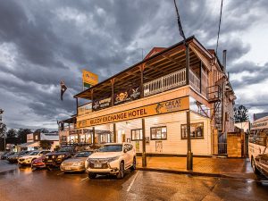 The Exchange Hotel Kilcoy, front of the building in the early evening. Its a two story building with cars parked out the front (reversed in). It looks like it has been raining with grey clouds in the background.